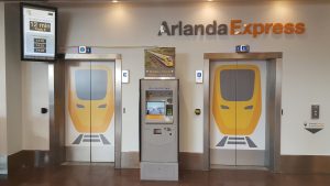 Arlanda Express ticket vending machine placed between elevator doors illustrated with painted train. Photo.