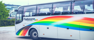 Side of a bus with painted rainbow coloured banner, which is part of the Flygbussarna logo. Photo.