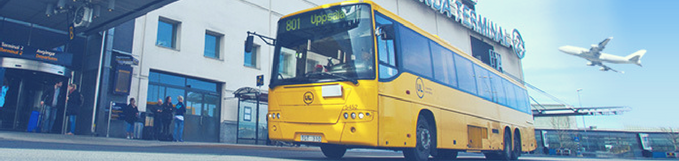 A bright yellow bus parked outside an entrance marked terminal. Photo.